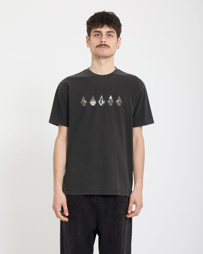 A young man with short dark hair and a mustache wears the Volcom Men's Lunar Phases Short Sleeve Tee, featuring small geometric designs across the chest, standing against a plain white background.
