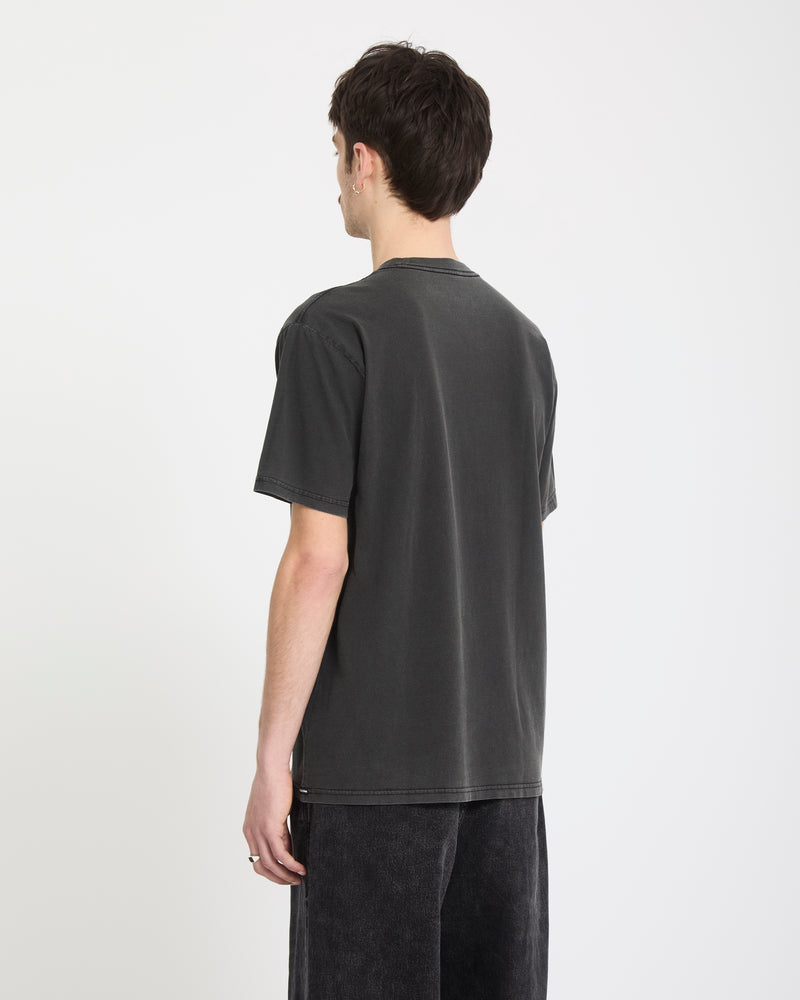 A person with short dark hair, wearing the Volcom Men's Lunar Phases Short Sleeve Tee in black and dark pants, stands with their back to the camera against a plain white background.