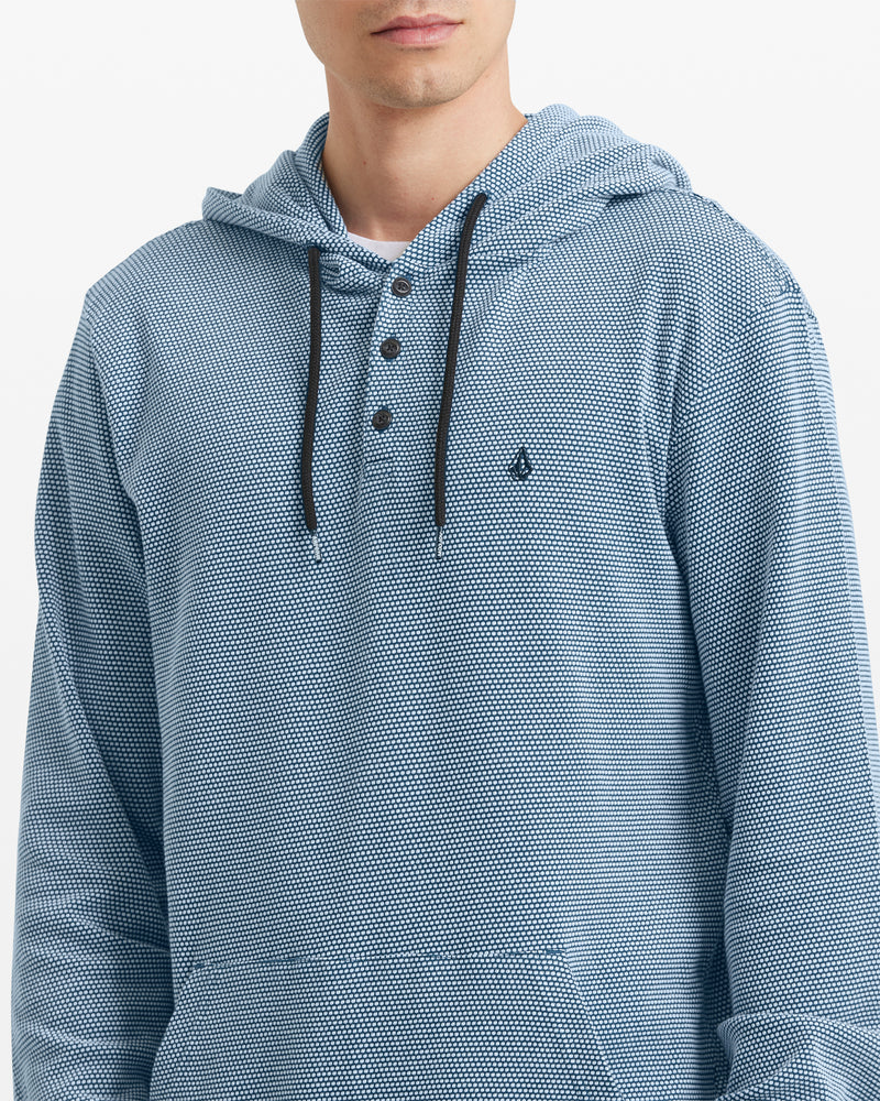 A man wears the Volcom Men's Murph Thermal Long Sleeve—a light blue waffle knit hoodie with black drawstrings, Henley placket, and small chest logo. His face is partially out of frame.