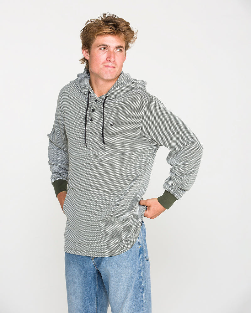 A person wearing the Volcom Men's Rowan Thermal Long Sleeve Shirt in gray, styled with blue jeans, stands with one hand on their hip and looks off to the side against a plain white background.