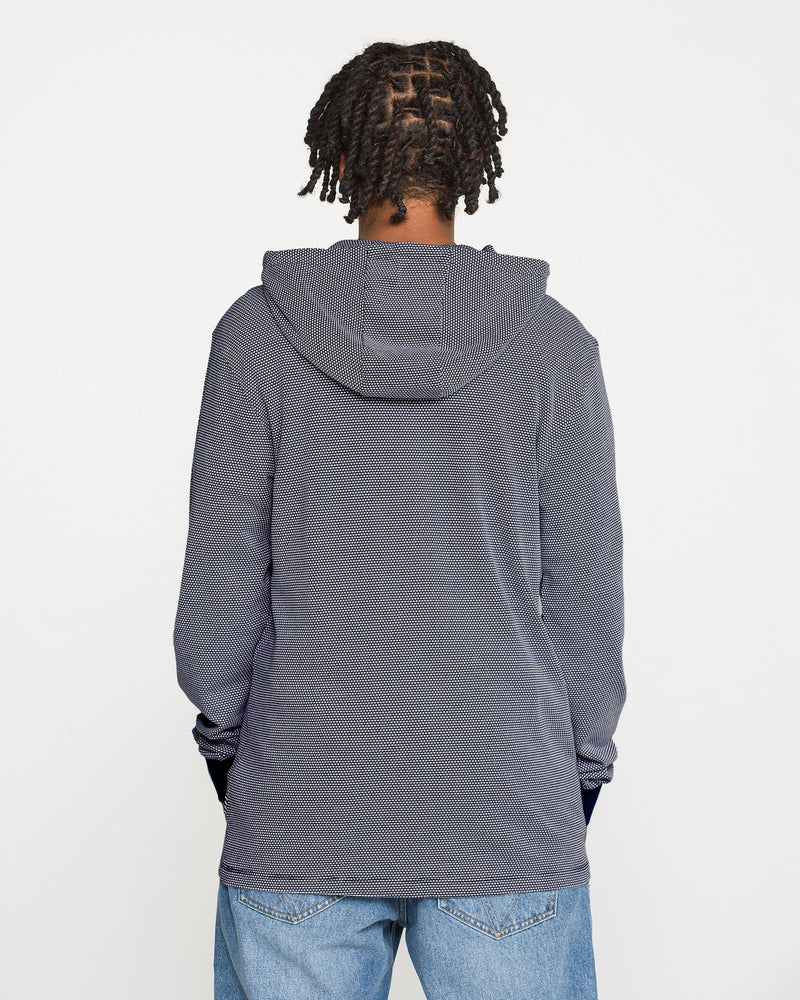 A person with short, twisted braids wears the Volcom Men's Rowan Thermal Long Sleeve Shirt in gray, paired with blue jeans, standing with their back to the camera against a plain white background.