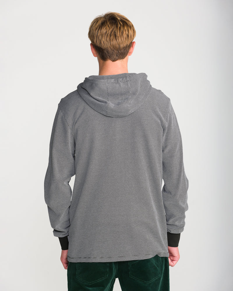 Back view of a person wearing a grey and white Men’s Rowan Thermal Long Sleeve, a popcorn knit hooded shirt with black cuffs.