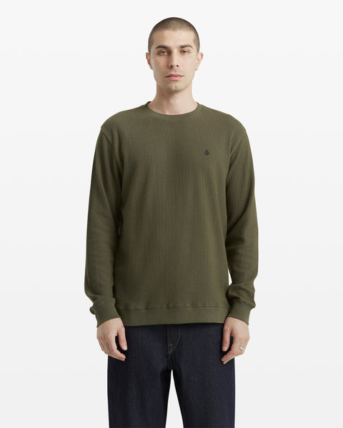 A person with short hair wears the Volcom Men's Gridstone Crew Long Sleeve in olive green and dark jeans, standing against a plain white background.