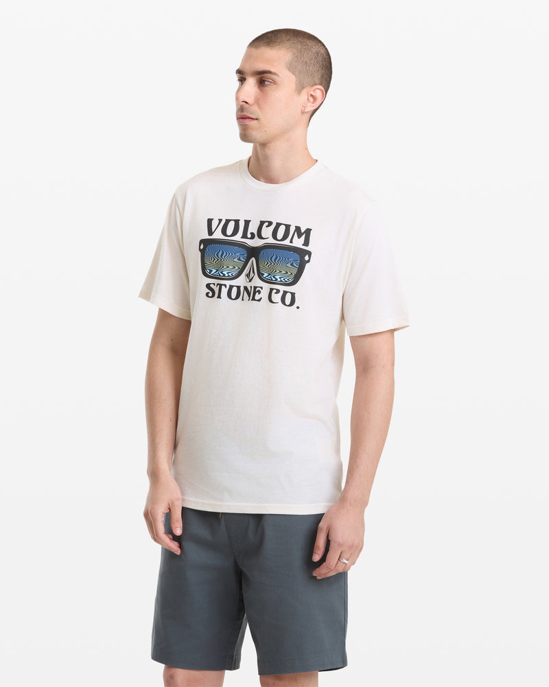 A man models the Volcom Men's Sunnies Short Sleeve Tee, featuring a sunglasses graphic and "VOLCOM STONE CO." text, paired with dark shorts against a plain white background while looking slightly to the side.