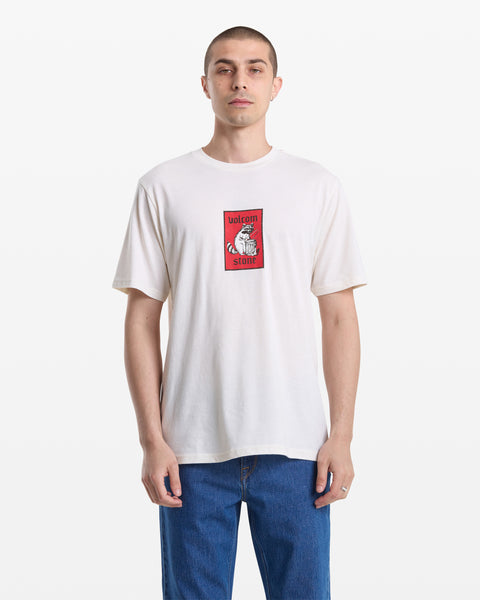 A man with short hair wears the Volcom Men's Rockout Short Sleeve Tee in white with a red graphic and blue jeans, standing forward against a plain white background.