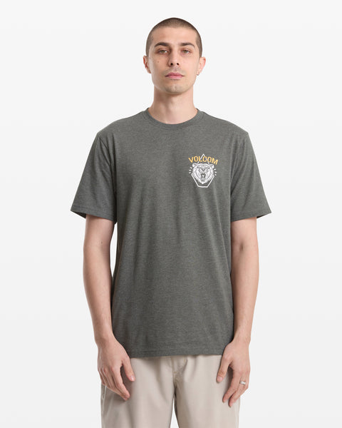 A man wears the Volcom Men's Golden Statement Short Sleeve Tee in gray, featuring a small white and yellow left chest graphic, against a plain white background.