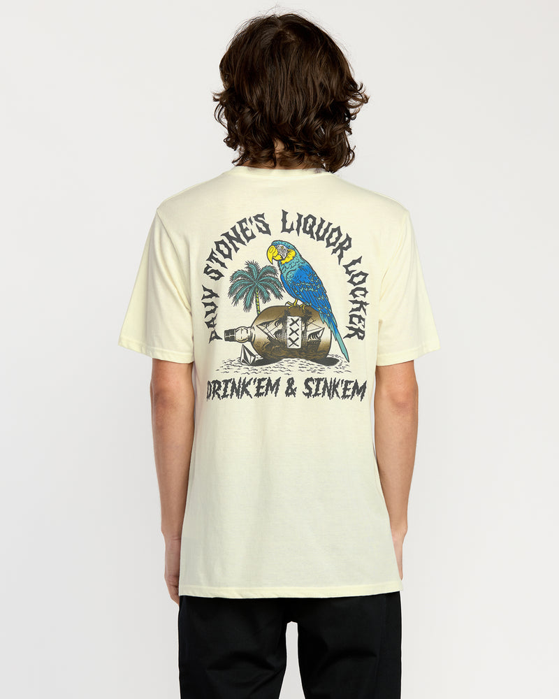 A person with medium-length brown hair faces away, wearing the Volcom Men's Rambln Short Sleeve Tee, a relaxed fit cotton blend featuring a screen print of a blue and yellow parrot on a barrel with palm trees and "DAVY JONESS LIQUOR LOCKER DRINK EM & SINK EM" text.