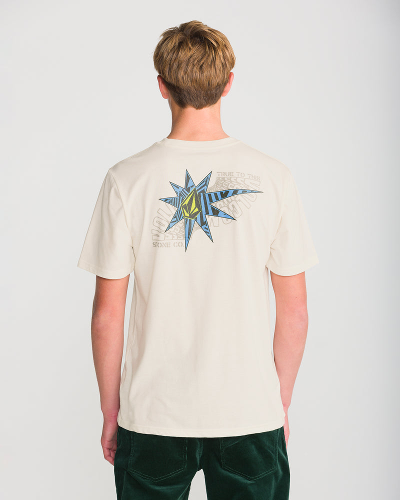 A man wearing a Volcom Men’s Op Blast Short Sleeve Tee, a cream-colored short-sleeve t-shirt with a blue and yellow star-shaped graphic on the back.