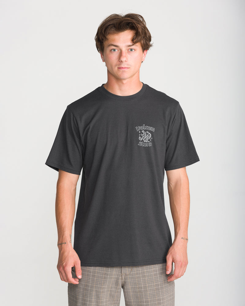 A man wearing a black Volcom Men’s Flash Short Sleeve Tee, a modern fit, crew-neck t-shirt featuring a small white logo on the left chest.