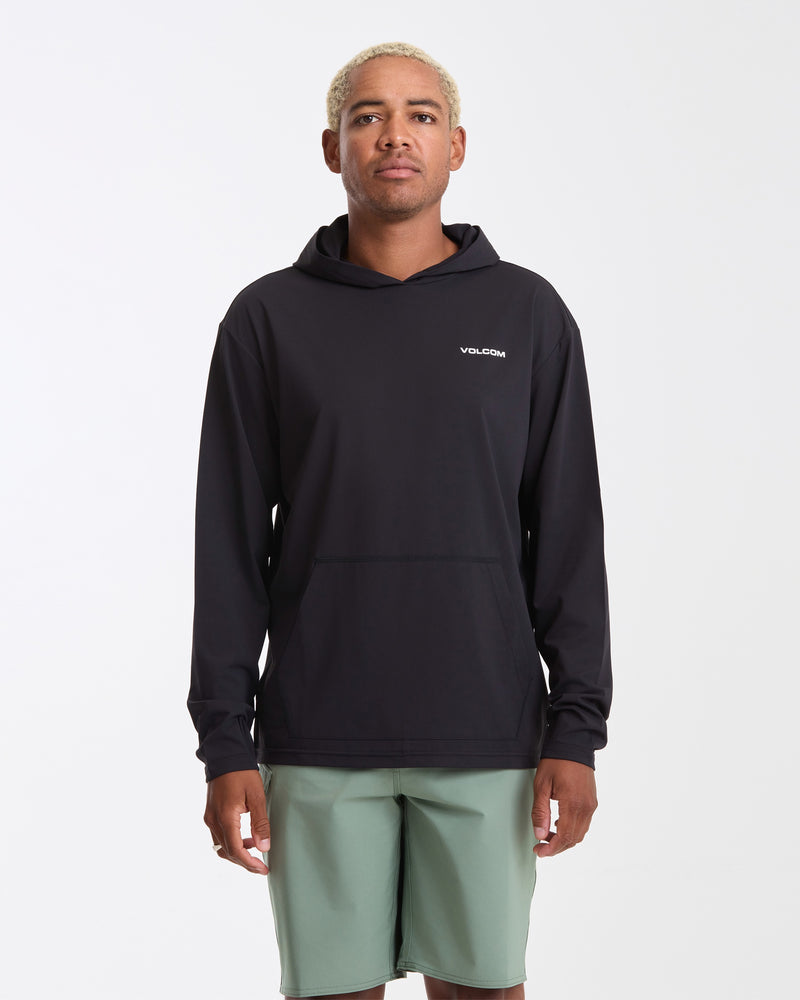 A person with short blond hair wears a black Volcom Men's Pullover Hood Long Sleeve and light green shorts, standing facing forward against a plain white background.