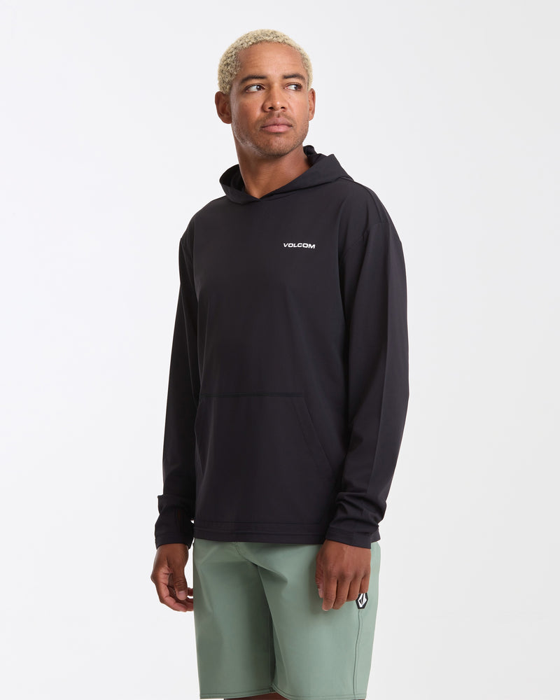 A person with short blond hair wears a black Volcom Men's Pullover Hood Long Sleeve and light green shorts, standing against a plain white background while looking to the side.