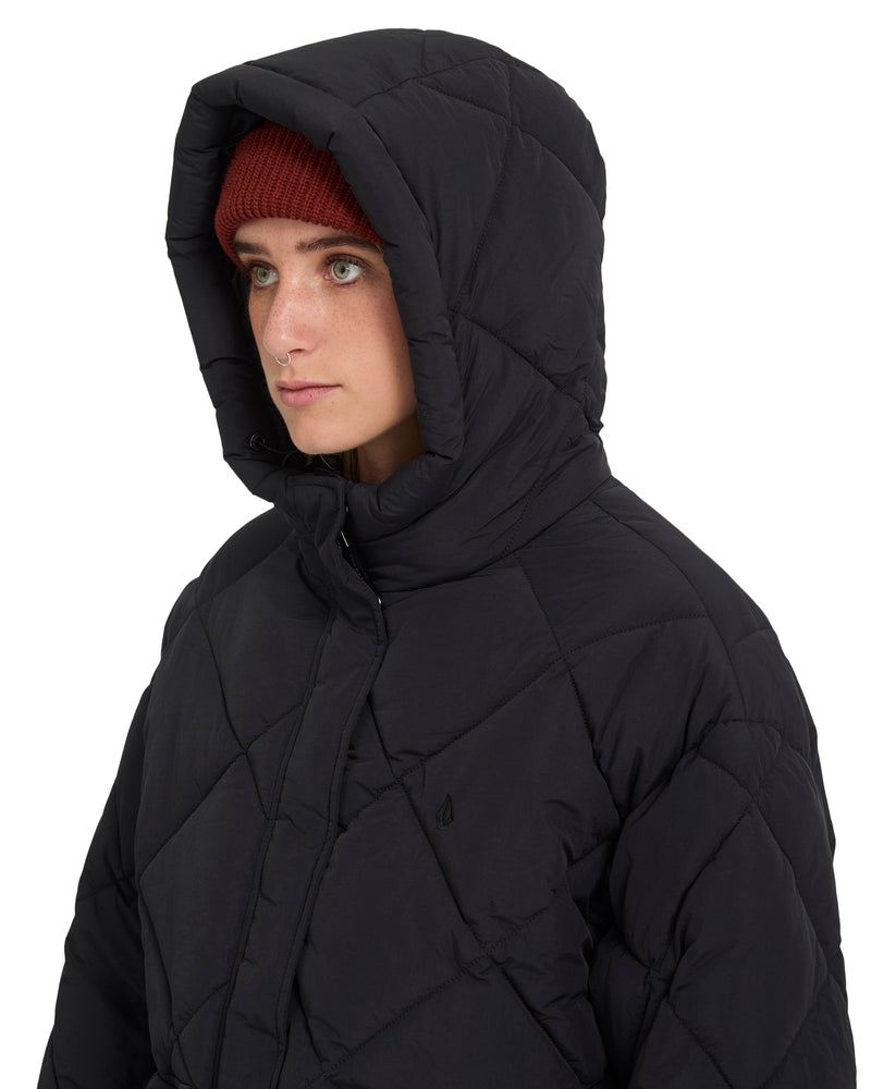 A person wearing a black, cropped, heavyweight Volcom Women’s Out Of Boxy Puff with a hood and a red beanie.