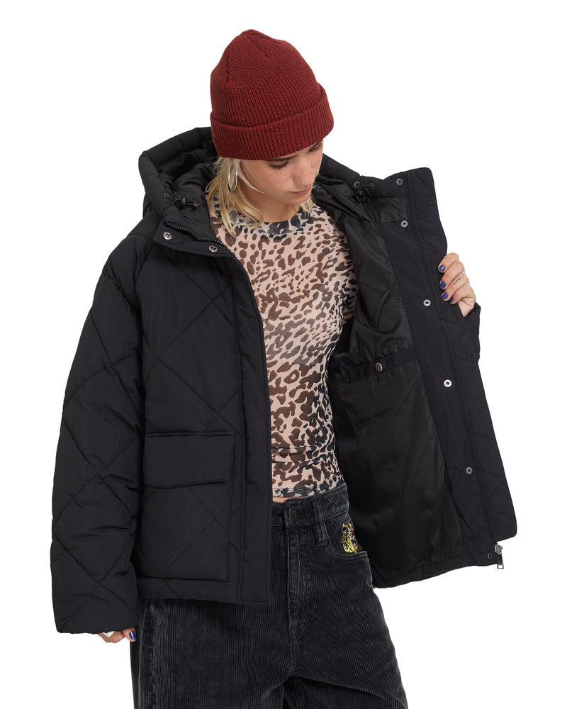 A woman wearing a maroon beanie and a black Volcom Women’s Out Of Boxy Puff cropped jacket, shown with the front open to reveal the lining.