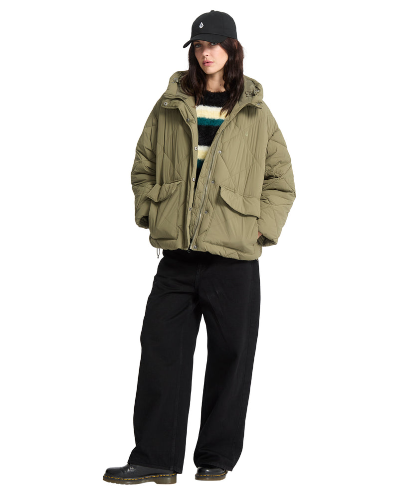 A person wearing a hooded, heavyweight olive green Volcom Out Of Boxy Puff, a striped sweater, and black pants.