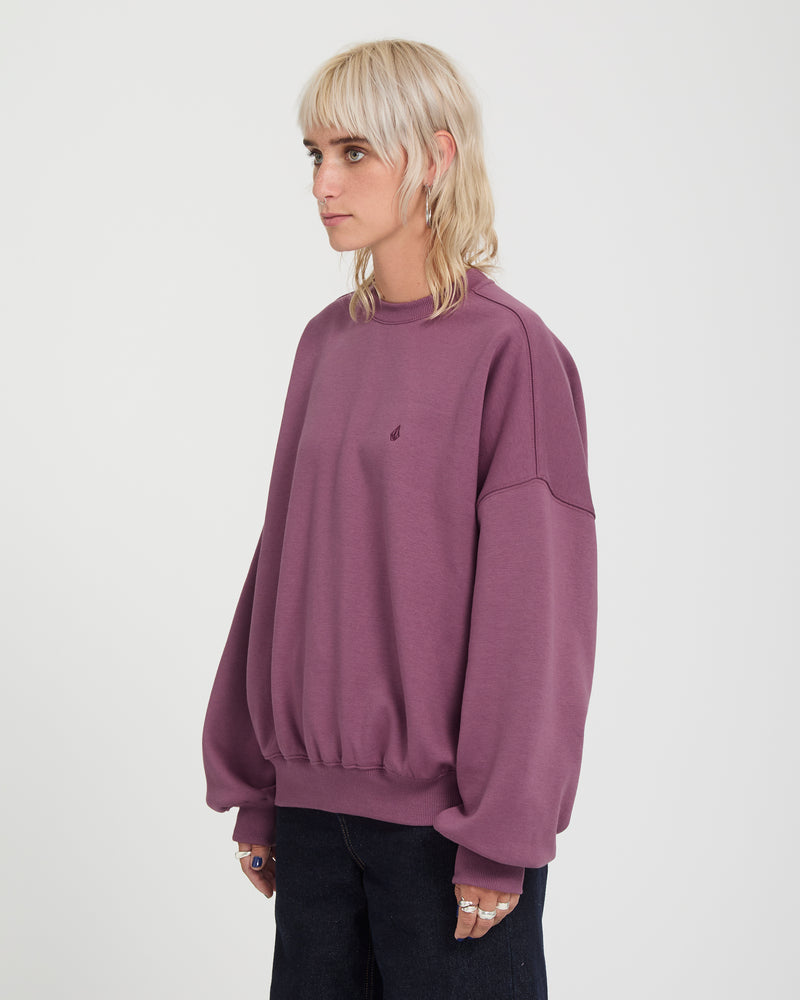 A person wears an oversized, plum-colored Volcom Sto N Crew heavyweight crewneck sweatshirt.
