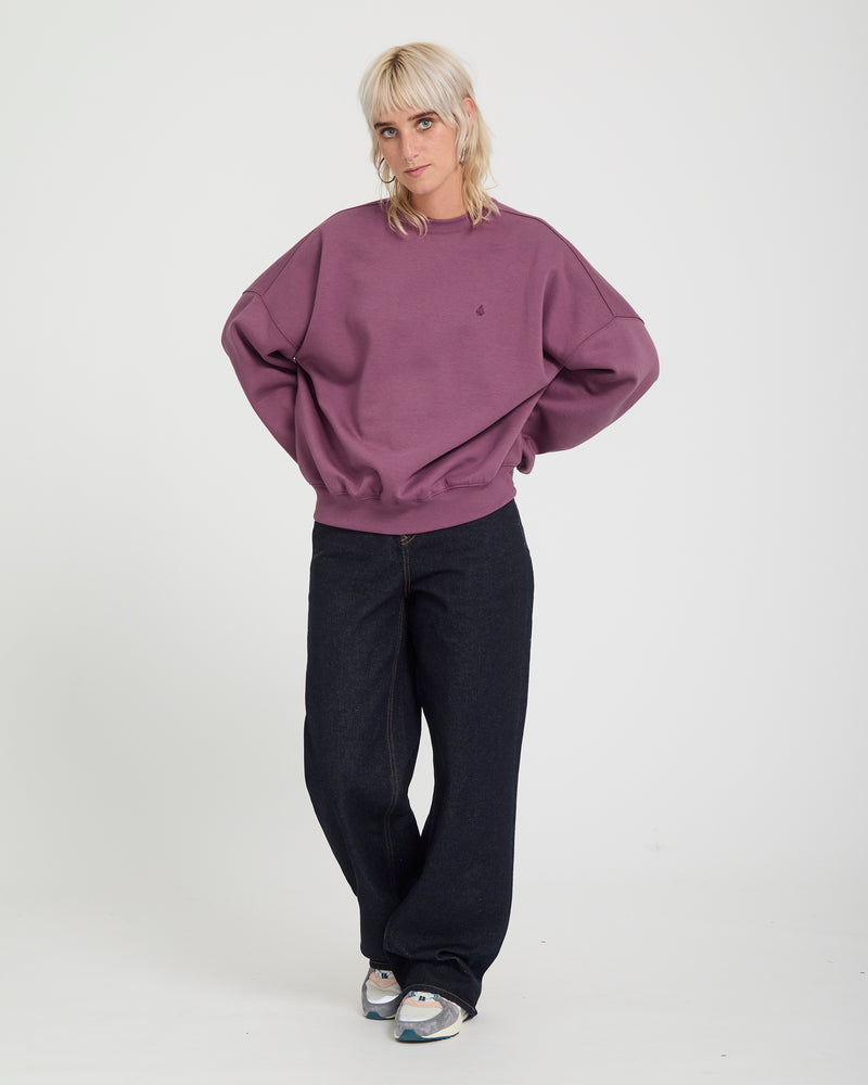A person wearing a Volcom Sto N Crew oversized heavyweight crewneck sweatshirt and dark blue wide-leg jeans.