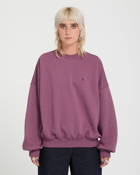 A person wears a long-sleeved, oversized plum-colored Volcom Sto N Crew heavyweight crewneck sweatshirt.
