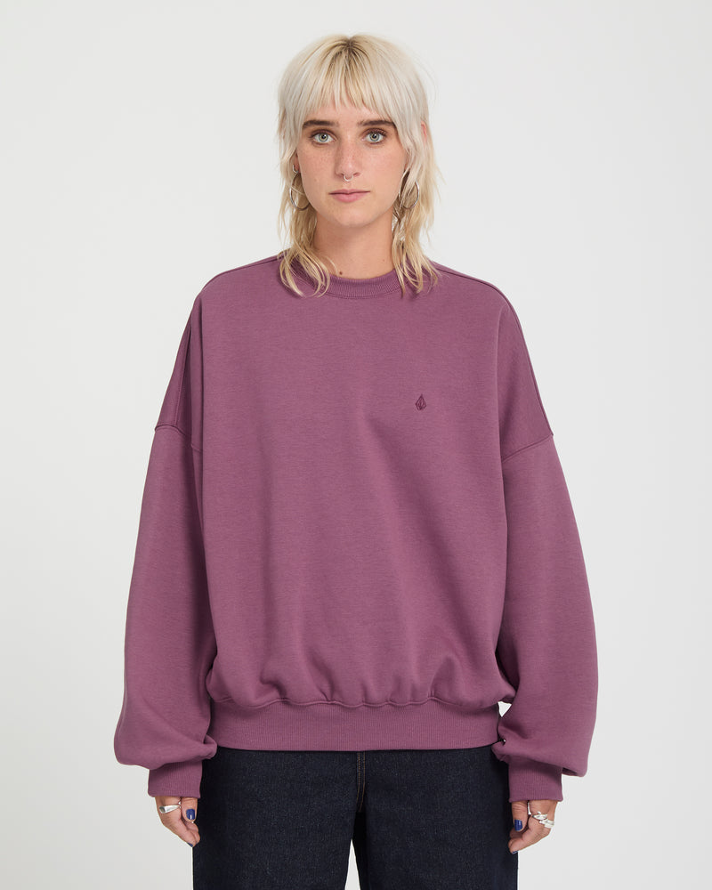 A person wears a long-sleeved, oversized plum-colored Volcom Sto N Crew heavyweight crewneck sweatshirt.