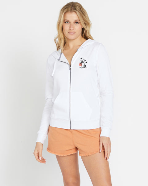 A blonde woman wears the Volcom Women's Sealed Zip Hoodie with a small palm tree graphic and peach shorts, standing against a plain white background.