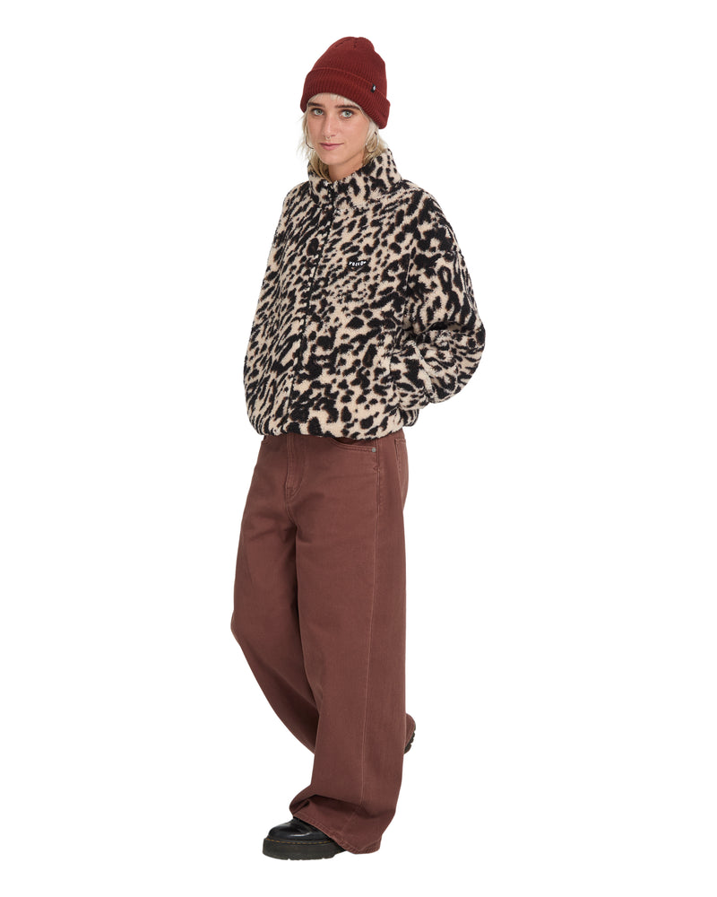 A person wearing an oversized Volcom Wylding Out Sherpa jacket with a leopard print, a maroon beanie, and brown wide-leg pants.