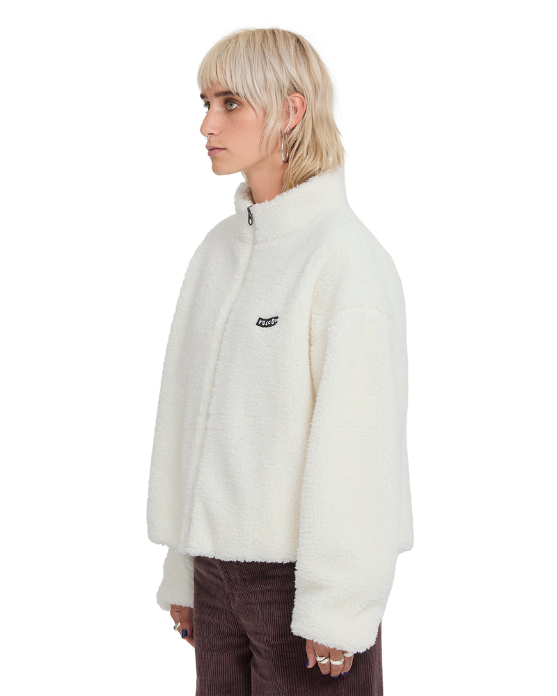 Side view of a person wearing an off-white Volcom Women’s Wylding Out Sherpa, an oversized zip-up jacket with a high collar.