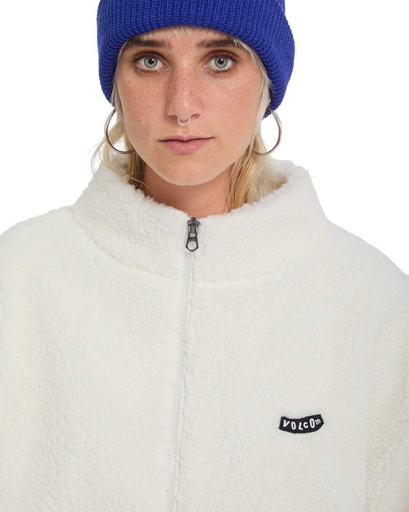 A person wearing an oversized Volcom Women’s Wylding Out Sherpa zip-up jacket and a blue beanie.