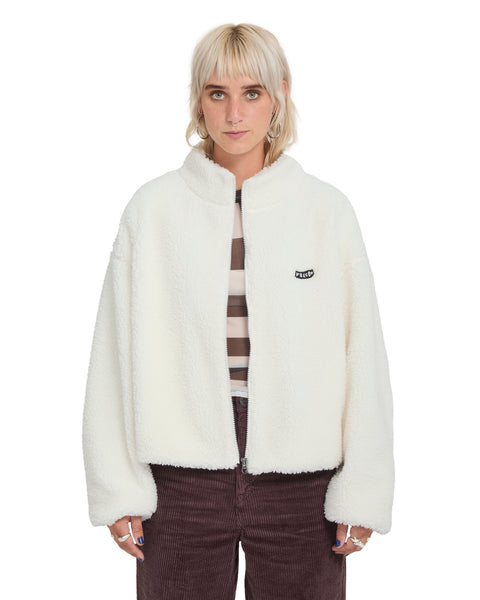 A person wears an oversized, cream-colored Volcom Women’s Wylding Out Sherpa zip-up fleece jacket with a small black logo patch on the chest.