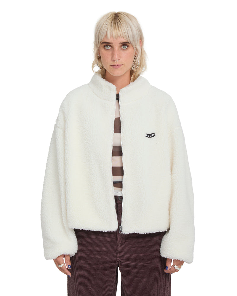A person wears an oversized, cream-colored Volcom Women’s Wylding Out Sherpa zip-up fleece jacket with a small black logo patch on the chest.