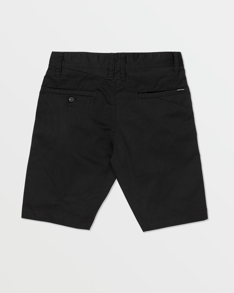 The Volcom Kids' Frickin Chino Shorts 16" are black, knee-length, shown from the back with a modern fit, belt loops, two rear pockets (one buttoned), and a black Volcom label above the right pocket. Shorts are laid flat on a white background.