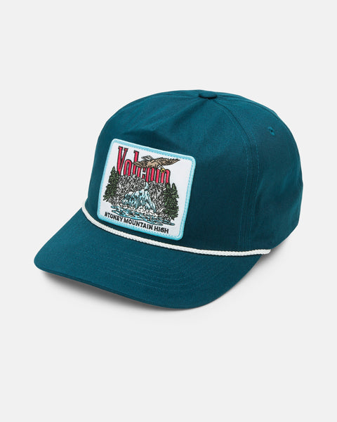 The Volcom Men's Stoney Mountain Hi Adjustable Hat is a teal cotton twill cap with a white rope above the brim and an embroidered patch featuring mountains, trees, Volcom text, and "Stoney Mountain High" at the bottom.