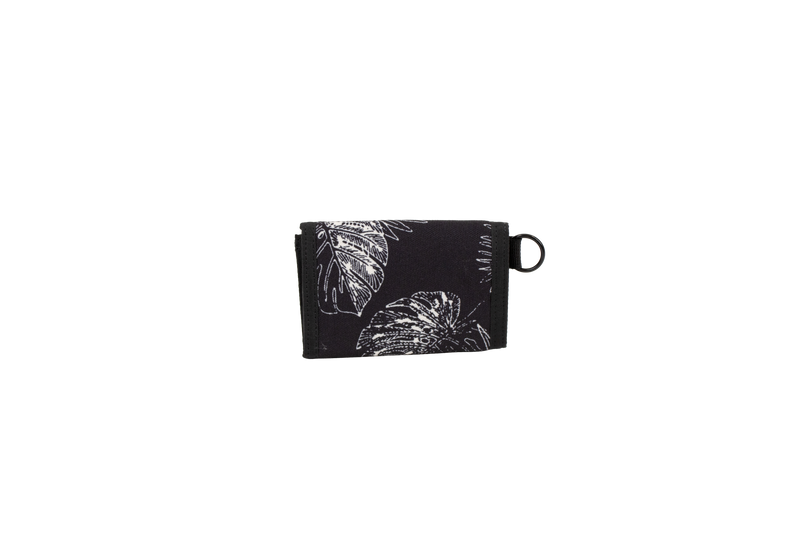 A black cotton canvas wallet with a white leaf and flower pattern, folded closed, featuring a small black loop on the right side, is displayed against a plain white background. The Men’s Box Stone Wallet from Volcom combines style and practicality in a compact design.