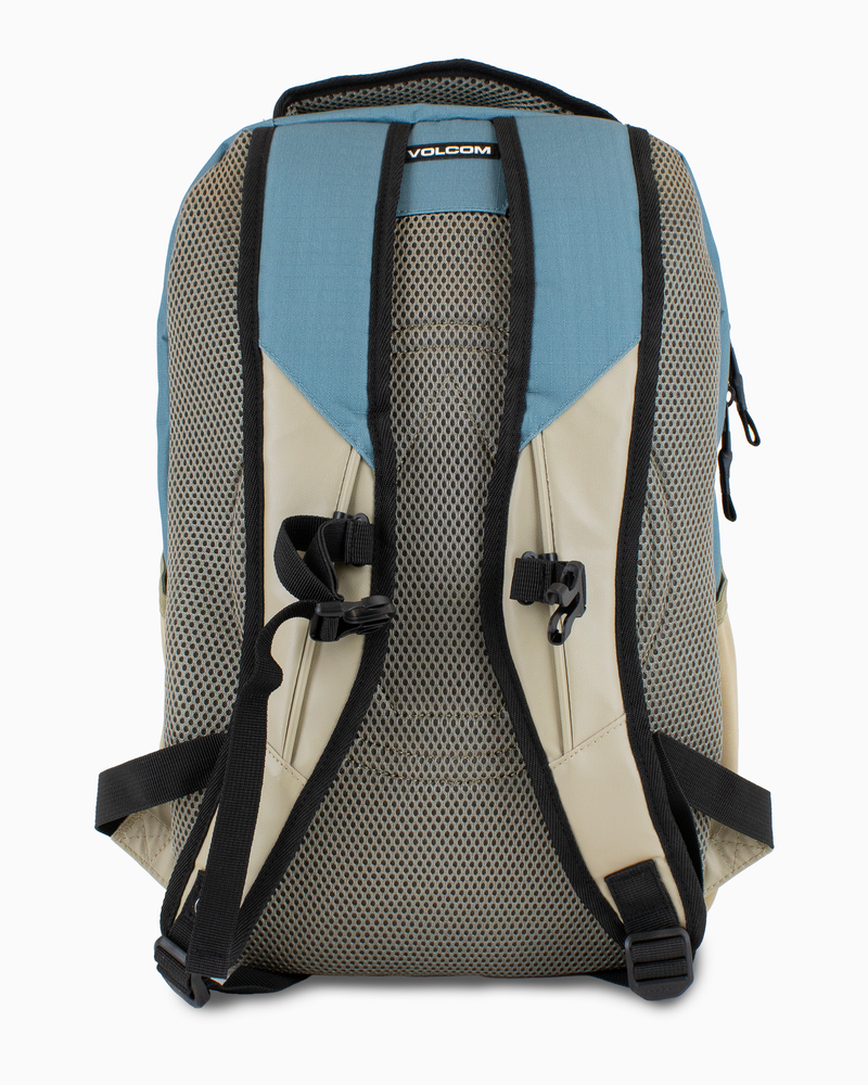 The Volcom Men's Grindstone Skate Backpack is shown from the back against a white background, featuring a blue and beige design with ergonomic black straps and mesh padding.