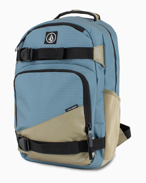 The Volcom Men's Grindstone Skate Backpack features a blue and khaki design with black ergonomic straps, front zippered pockets, a padded laptop sleeve, and a Volcom logo patch on the top pocket.