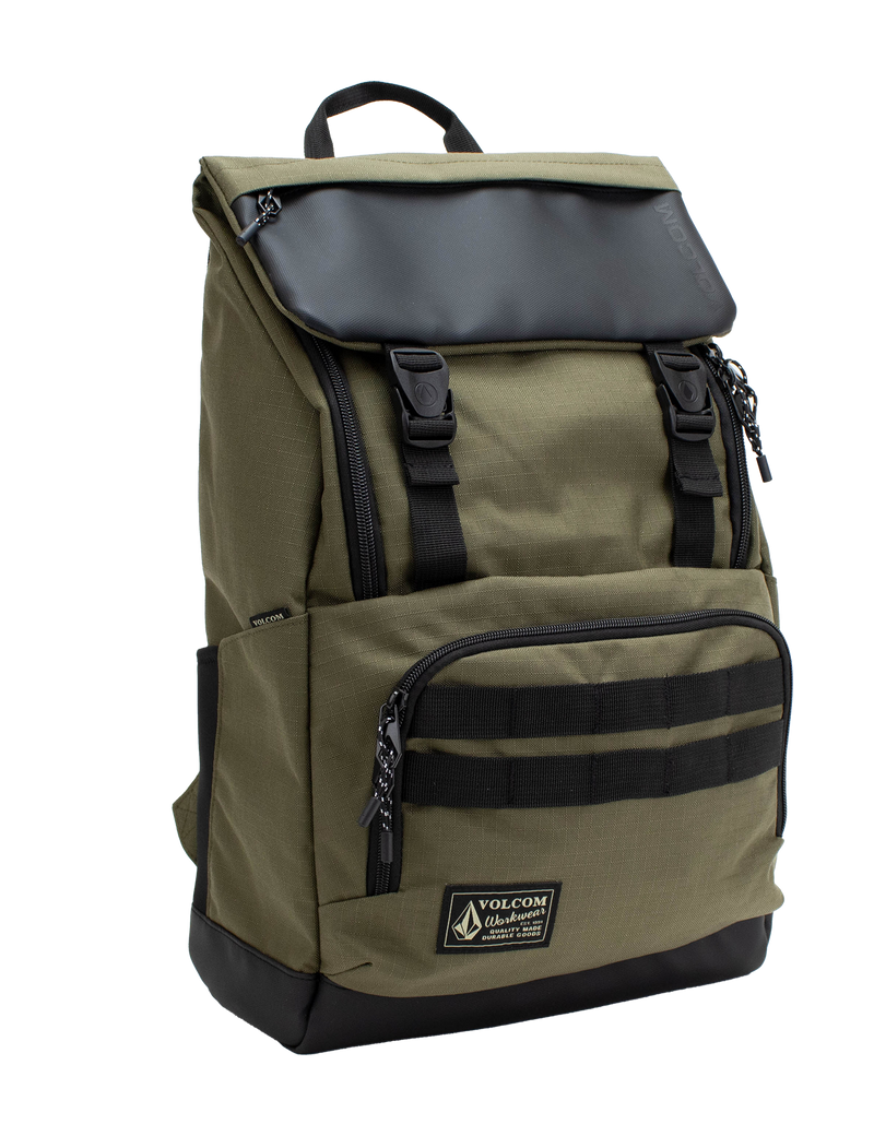 Men’s Charter Ruck Backpack by Volcom in olive green features a black flap, top handle, front zip pocket, and patch label. This workwear-inspired backpack has black straps, side pockets, and a rectangular silhouette shown against a white background.