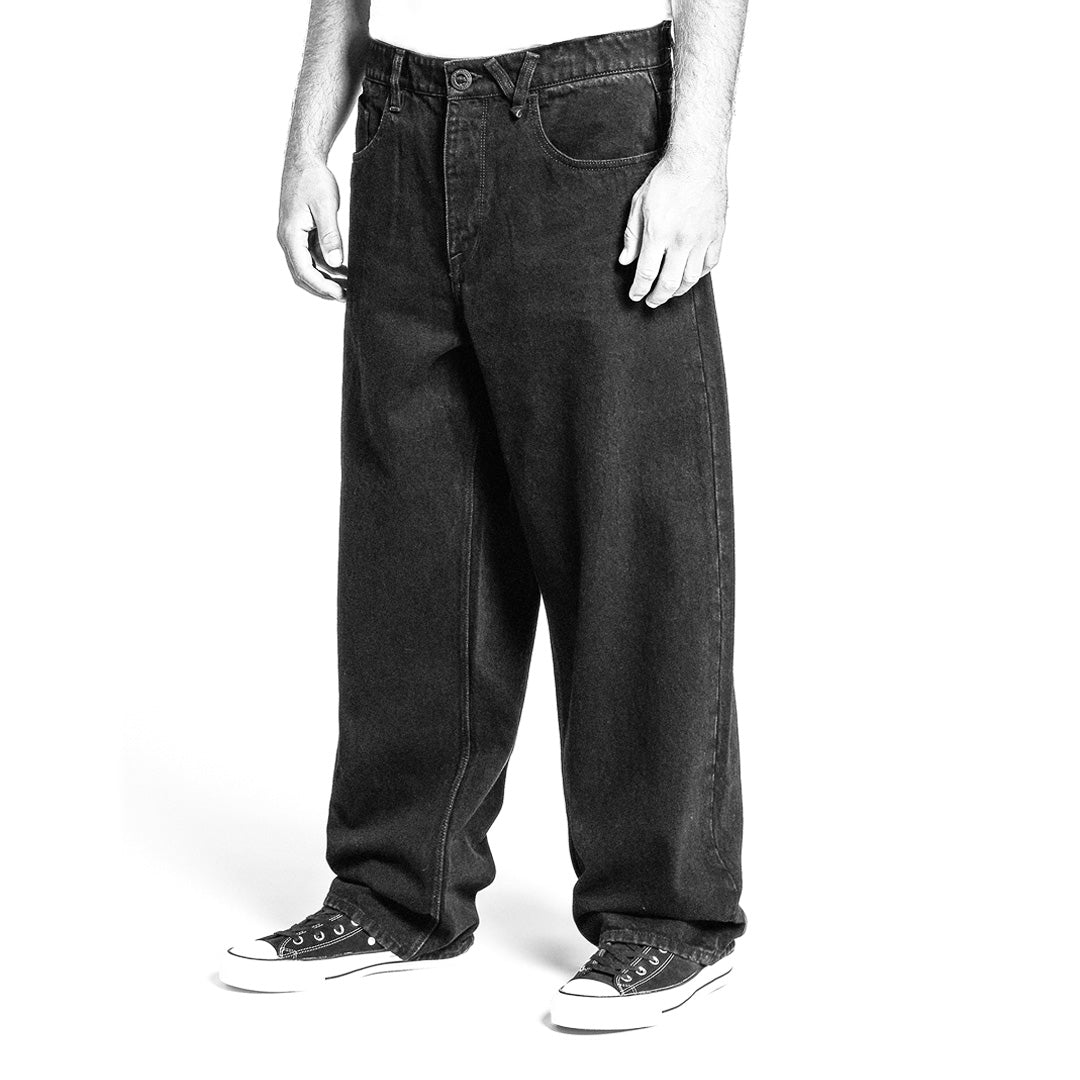 Black and white image of person wearing loose jeans and sneakers on a white background
