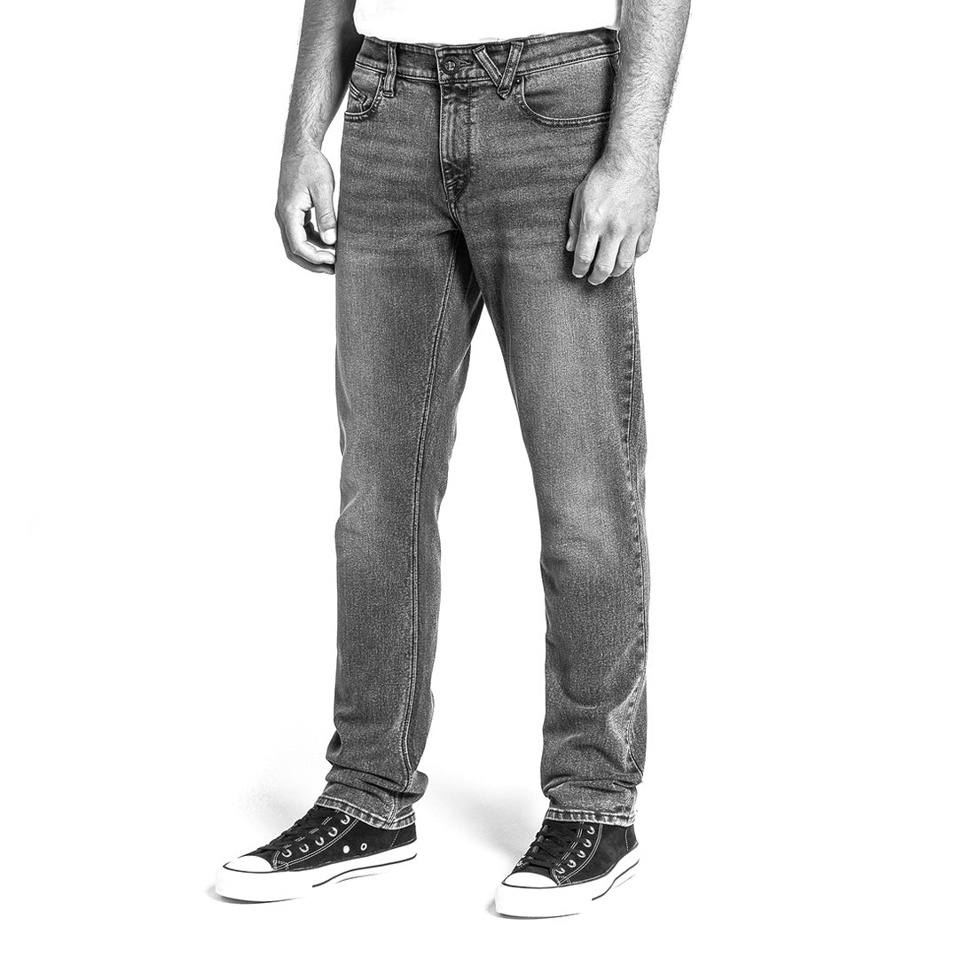 Black and white image of person wearing slim jeans and sneakers on a white background