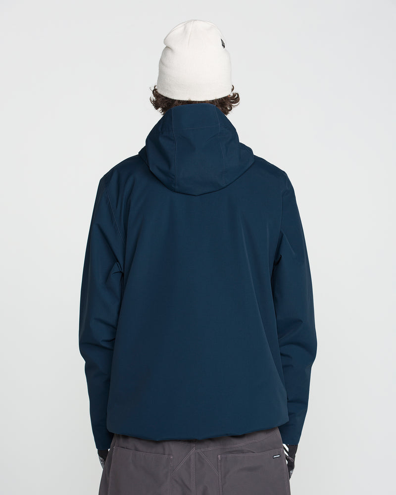 A person is seen from the back, standing against a plain light background, wearing a white beanie, gray pants, and the Volcom Men’s Double Insulated Jacket in navy, which features Zip Tech.