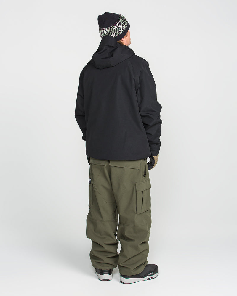 A person stands facing away, wearing the Volcom Men’s 2836 Insulated Jacket in black, paired with olive green cargo pants, black and white sneakers, and a black beanie with a white pattern. The background is plain white.