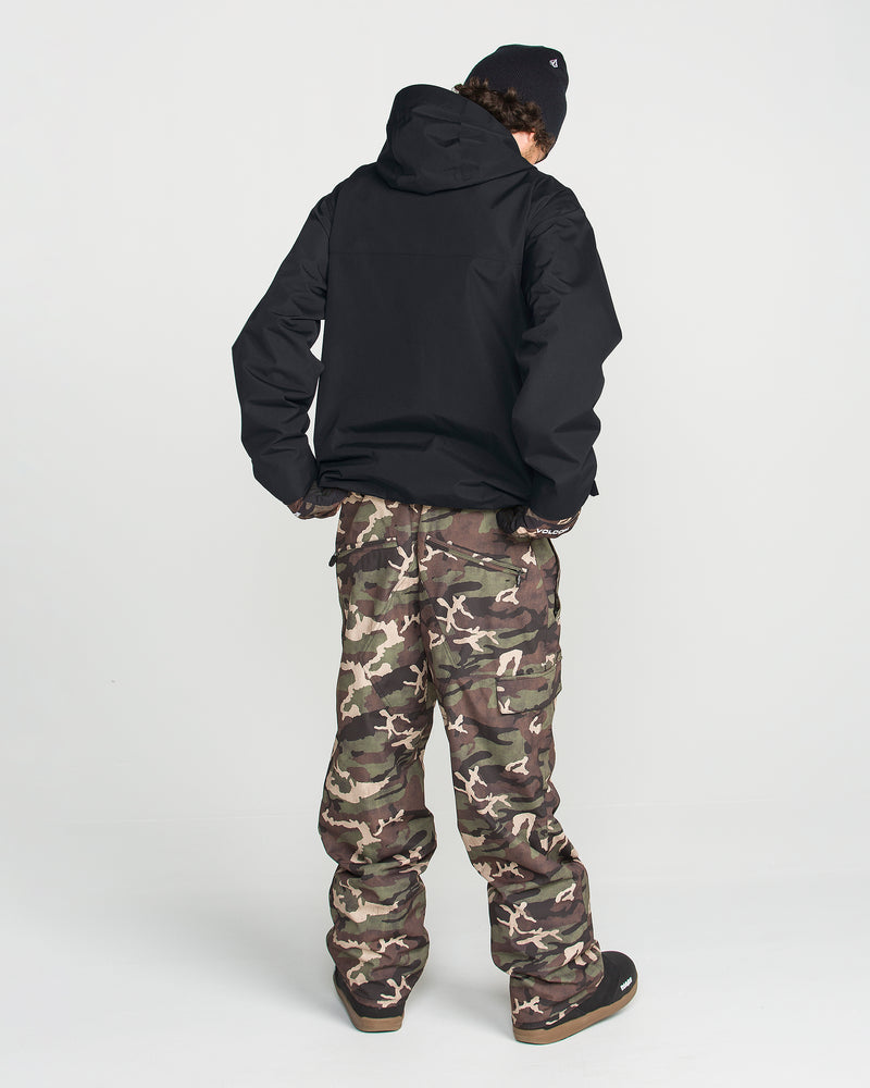 A person stands facing away from the camera against a plain white background, wearing the Volcom Men’s Buckthreeeighty Insulated Jacket in black, which features 10K waterproofing and is made from recycled fabric, paired with camouflage pants, a black beanie, and dark shoes.