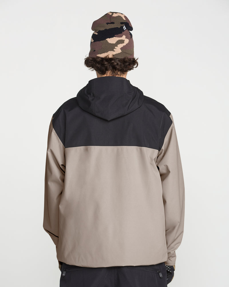 A person is standing with their back to the camera against a plain white background, wearing the Volcom Men’s Buckthreeeighty Insulated Jacket—a hooded, two-tone jacket made from recycled fabric—and a brown camouflage beanie.