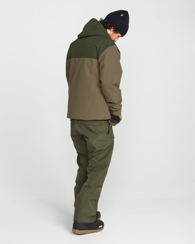 Wearing the Volcom Men’s Buckthreeeighty Insulated Jacket in olive green, along with matching pants, black gloves, and a black beanie, a person stands facing away against a plain white background.