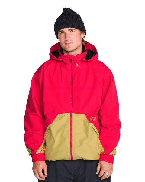 A person wearing a black beanie and a red and tan Men’s Longo Gore-Tex Jacket with ribbed cuffs.