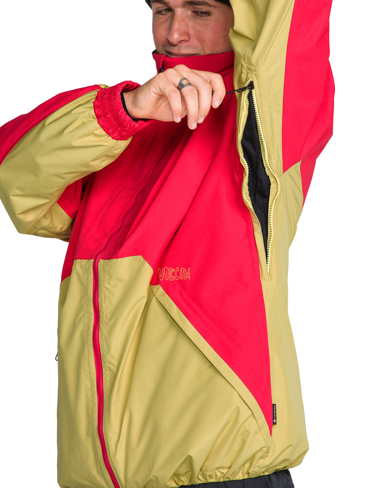 A person wears a red and tan color-blocked Men’s Longo Gore-Tex Jacket with an open underarm zipper vent.