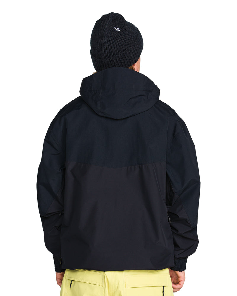 Back view of a person wearing a black Volcom Men’s Longo Gore-Tex Jacket and a dark beanie, paired with light-colored trousers.