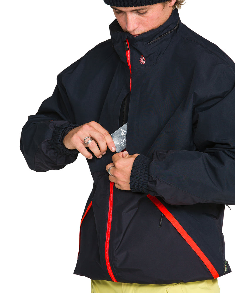 A person wearing a black Volcom Men’s Longo Gore-Tex Jacket with red trim and cuffs opens a front pocket.