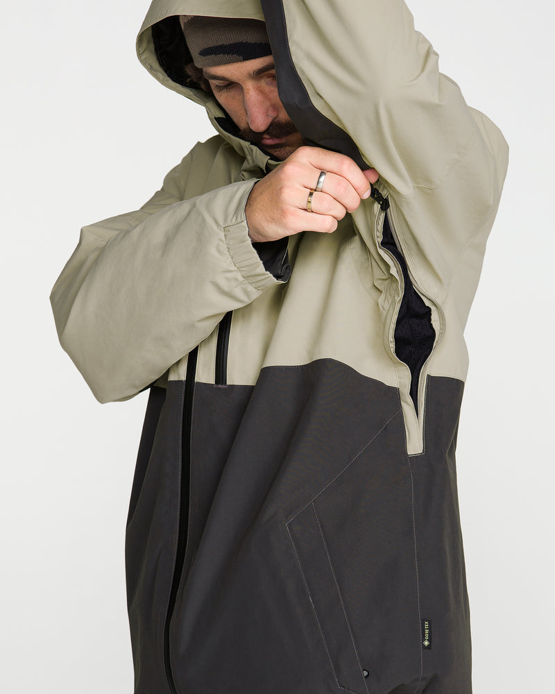 A person wearing the Volcom Men’s L Gore-Tex Jacket unzips an underarm vent while their head, slightly bowed, is partly covered by the jacket’s hood.