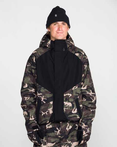 A person wearing a black beanie, black gloves, and the Volcom Men’s Collins 20K Jacket—crafted from a recycled shell with a camouflage pattern—stands facing forward against a plain white background.