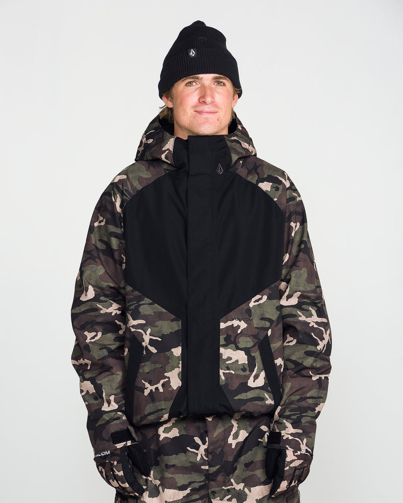 A person wearing a black beanie, black gloves, and the Volcom Men’s Collins 20K Jacket—crafted from a recycled shell with a camouflage pattern—stands facing forward against a plain white background.