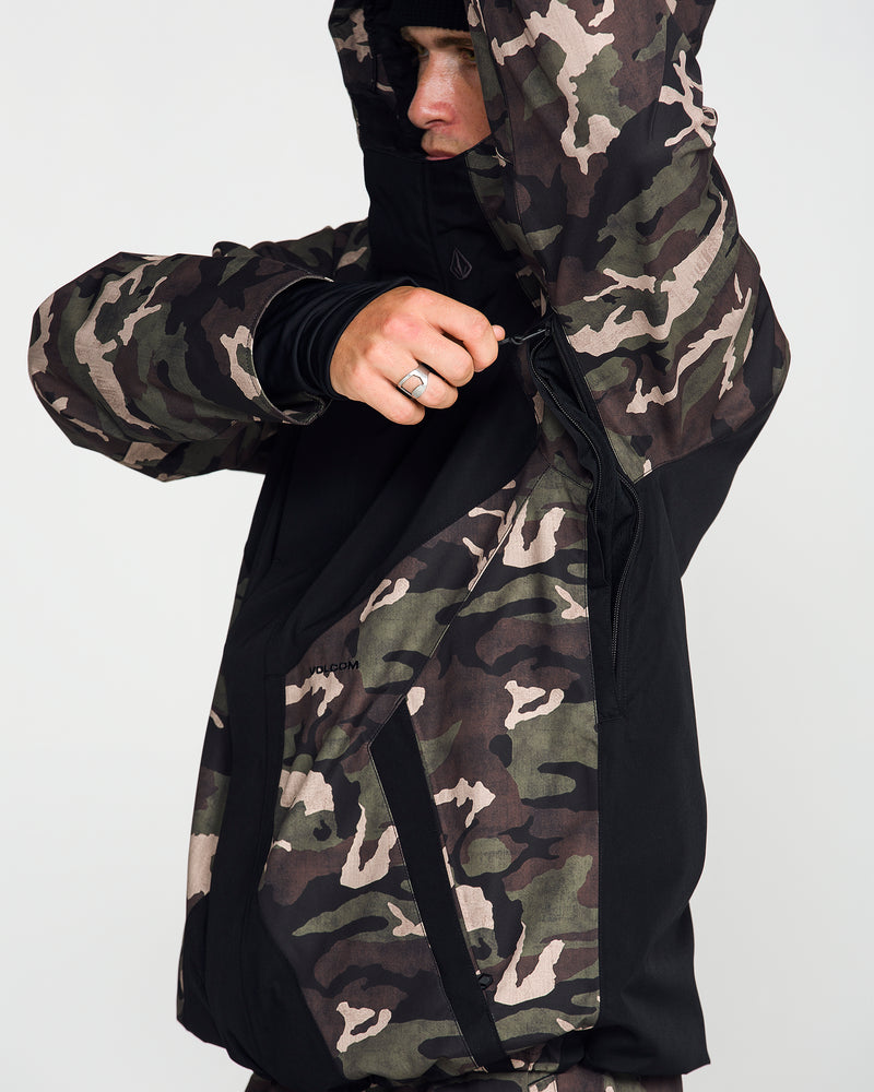 A person wearing the Volcom Men’s Collins 20K Jacket—a camouflage, waterproof ski jacket with a hood—unzips a black underarm side vent. Only part of their face is visible, and their hand, adorned with a silver ring, reveals a detail of the jacket’s sustainable recycled shell construction that blends style with eco-friendly performance.