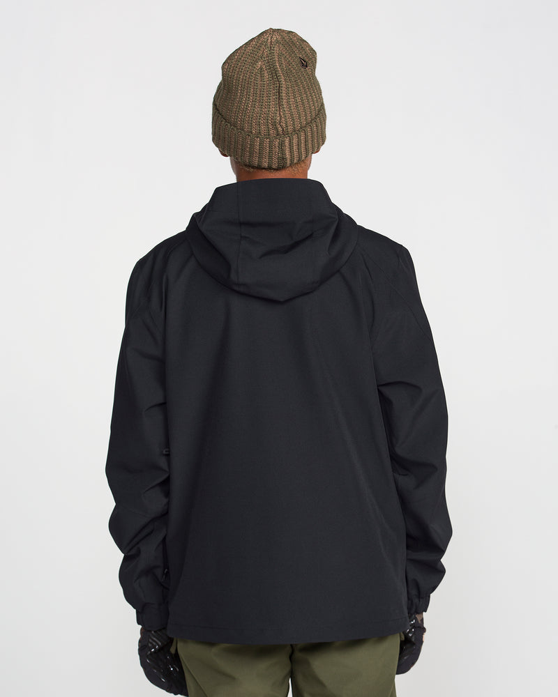 A person wearing a brown knit beanie, green pants, black gloves, and the Volcom Men’s Brighton Full Zip Jacket—featuring a black hood and crafted with V-Science 2-Layer shell and Repreve fibers—is standing with their back to the camera against a plain white background.